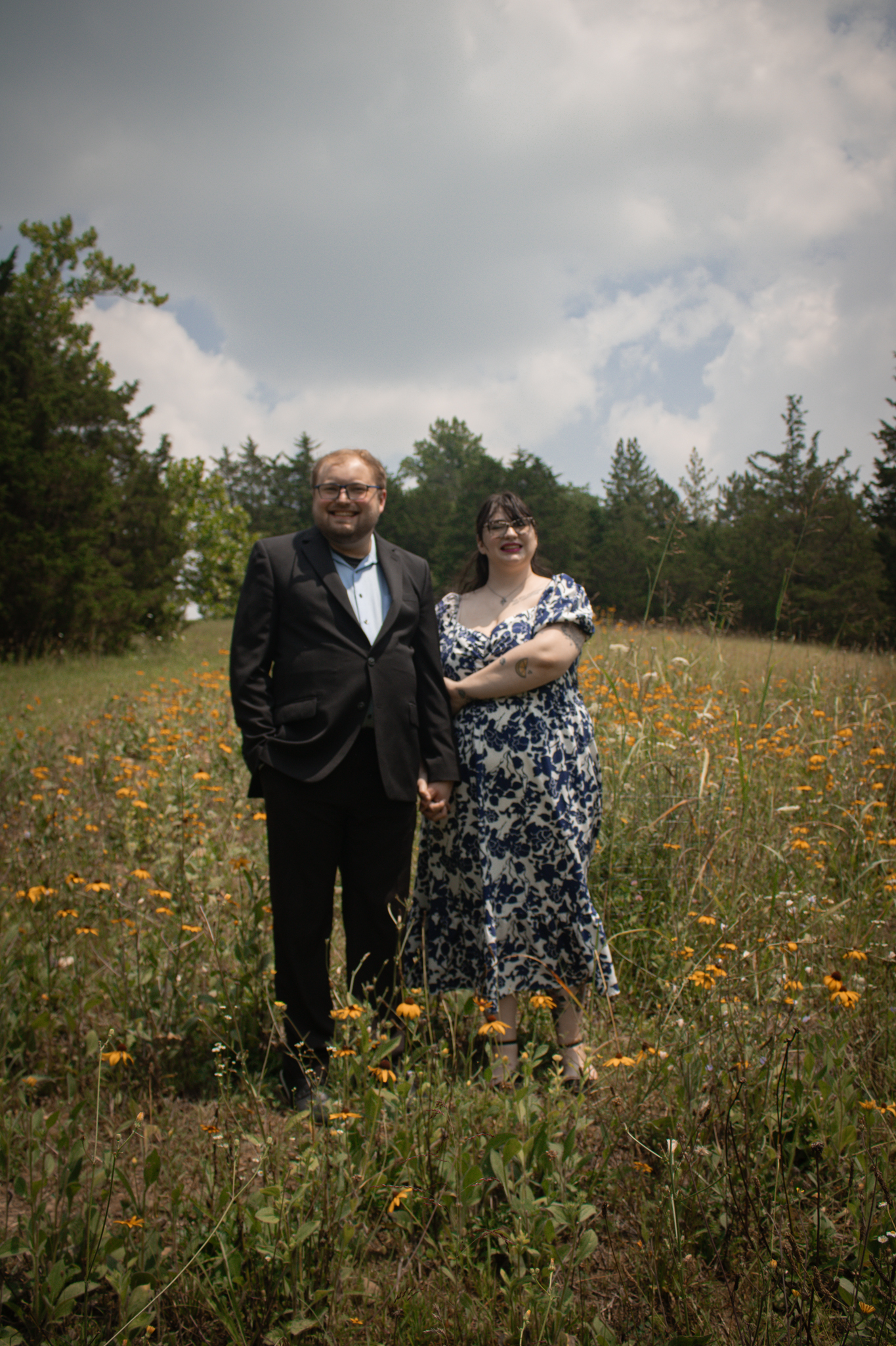 Sage and their husband holding hands in a field of flowers